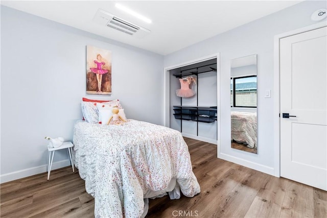 bedroom with wood finished floors, visible vents, and baseboards