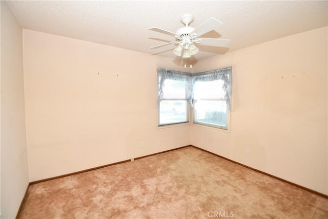 carpeted empty room with ceiling fan, baseboards, and a textured ceiling