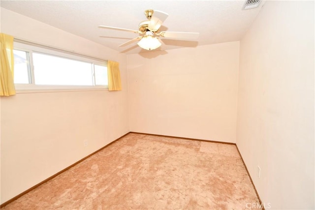 spare room with light carpet, ceiling fan, visible vents, and baseboards