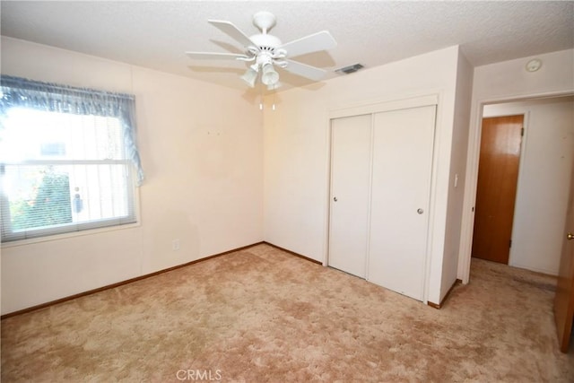 unfurnished bedroom featuring light colored carpet, a closet, visible vents, and a textured ceiling