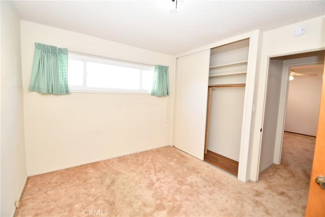 unfurnished bedroom with a textured ceiling, a closet, and carpet