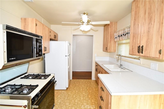 kitchen featuring range with gas stovetop, freestanding refrigerator, light countertops, black microwave, and a sink