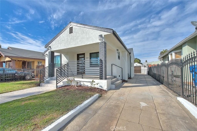 view of front of house featuring stucco siding, covered porch, driveway, and fence