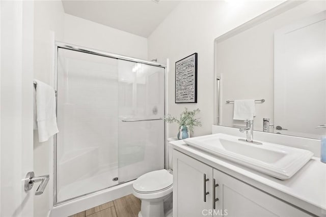 bathroom featuring toilet, a stall shower, wood finished floors, and vanity