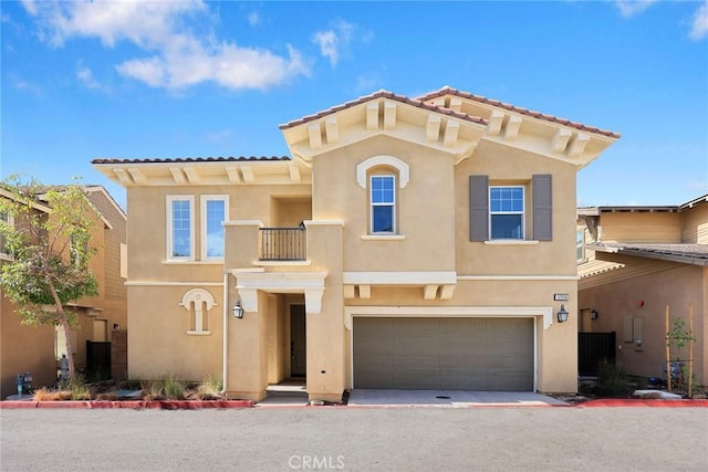 mediterranean / spanish house with a tiled roof, an attached garage, a balcony, and stucco siding