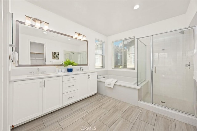 bathroom featuring a bath, a stall shower, double vanity, and a sink