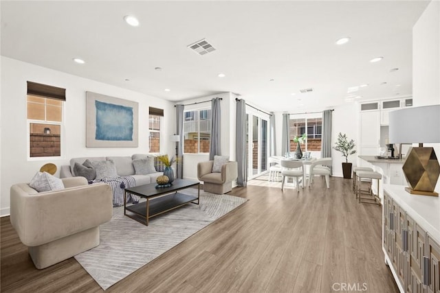 living room with light wood-type flooring, visible vents, and recessed lighting