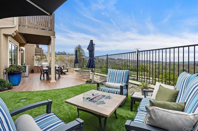 view of patio / terrace featuring an outdoor living space with a fire pit, fence, and a balcony