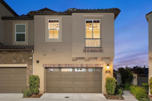 mediterranean / spanish house with a tiled roof, an attached garage, and stucco siding