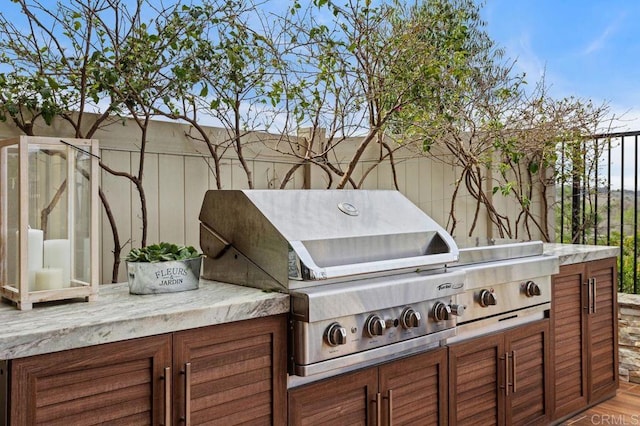 view of patio with exterior kitchen, area for grilling, and fence