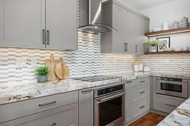 kitchen featuring wall chimney exhaust hood, gray cabinetry, black electric cooktop, and oven