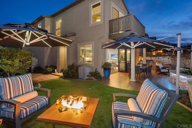 rear view of house with a patio area, an outdoor living space with a fire pit, a balcony, and stucco siding