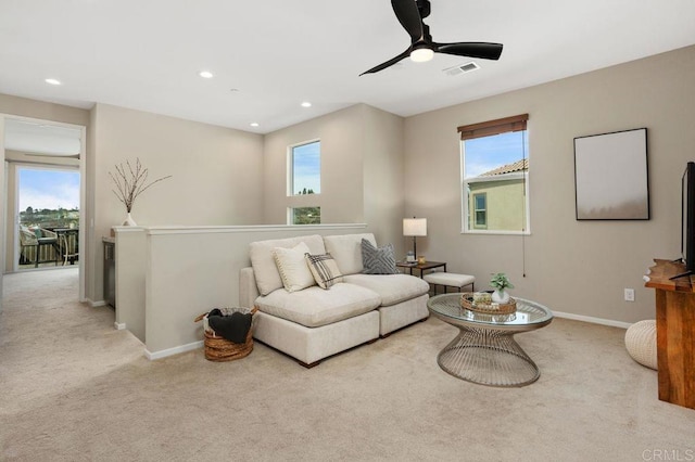 carpeted living area with visible vents, plenty of natural light, and baseboards