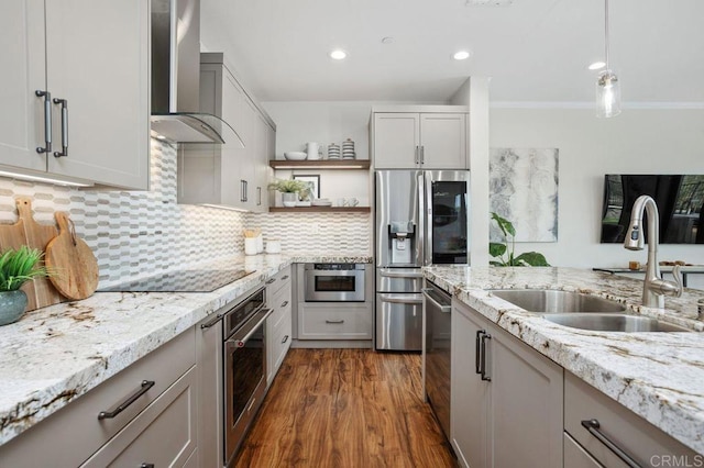 kitchen with a sink, wall chimney range hood, appliances with stainless steel finishes, dark wood-style floors, and tasteful backsplash