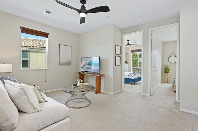 living area featuring carpet floors, visible vents, baseboards, and a ceiling fan