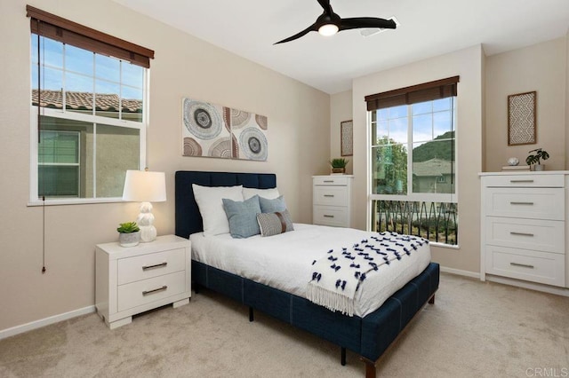 bedroom with baseboards, ceiling fan, multiple windows, and light colored carpet