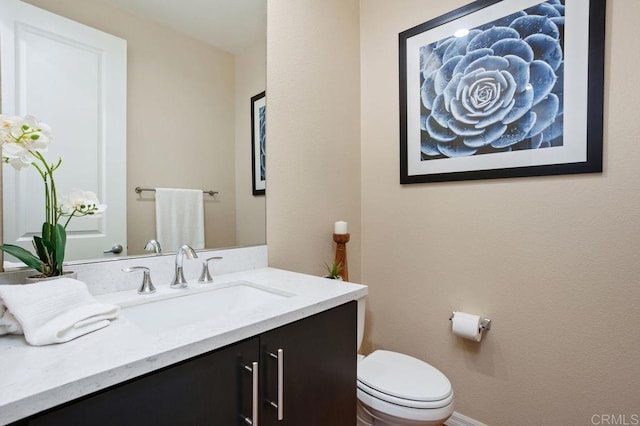 half bath featuring toilet, baseboards, and vanity