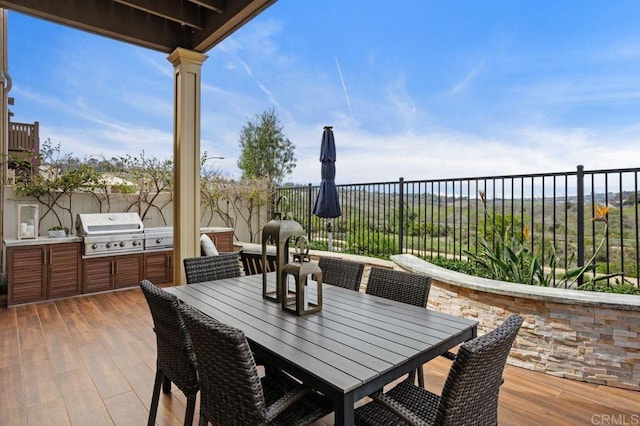 view of patio / terrace featuring exterior kitchen, outdoor dining space, a grill, and fence