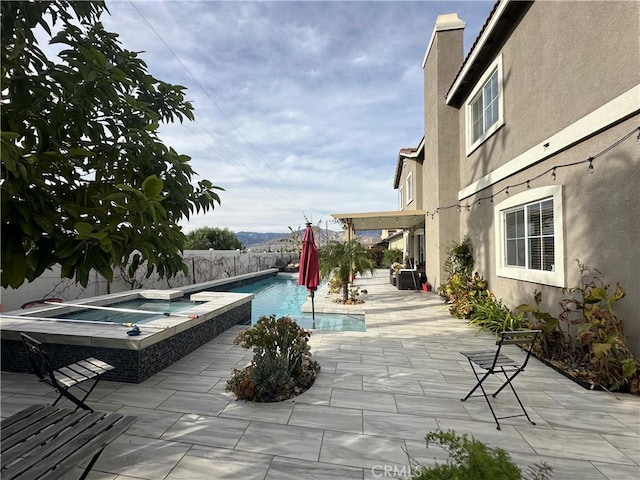 outdoor pool with a patio area, a fenced backyard, and an in ground hot tub