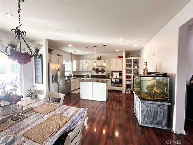 kitchen featuring stainless steel appliances, dark wood-type flooring, dark countertops, and white cabinetry