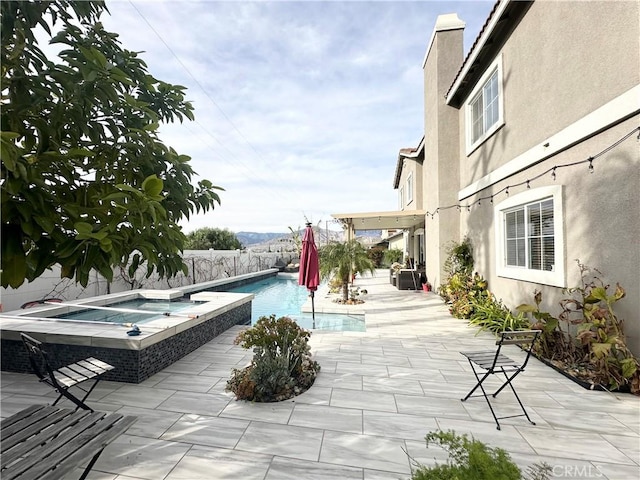 outdoor pool with an in ground hot tub, a patio area, and a fenced backyard