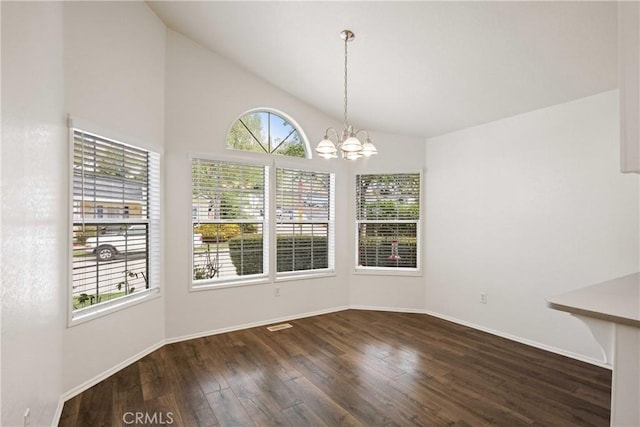 unfurnished dining area with lofted ceiling, baseboards, wood finished floors, and an inviting chandelier