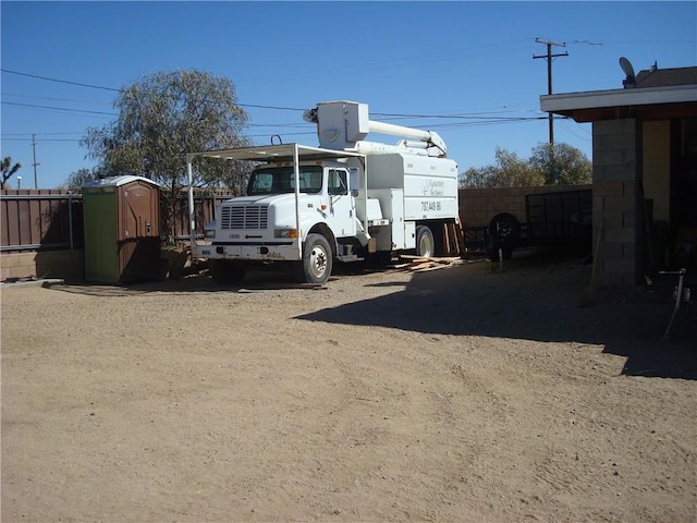 view of yard with an outbuilding, fence, and a shed