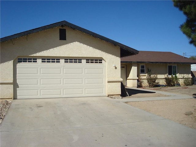 ranch-style home featuring a garage, concrete driveway, and stucco siding