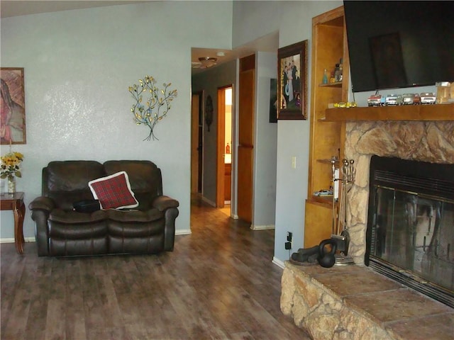 living area featuring a fireplace, baseboards, and wood finished floors