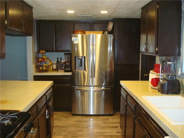 kitchen featuring appliances with stainless steel finishes, light countertops, a textured ceiling, light wood-type flooring, and a sink