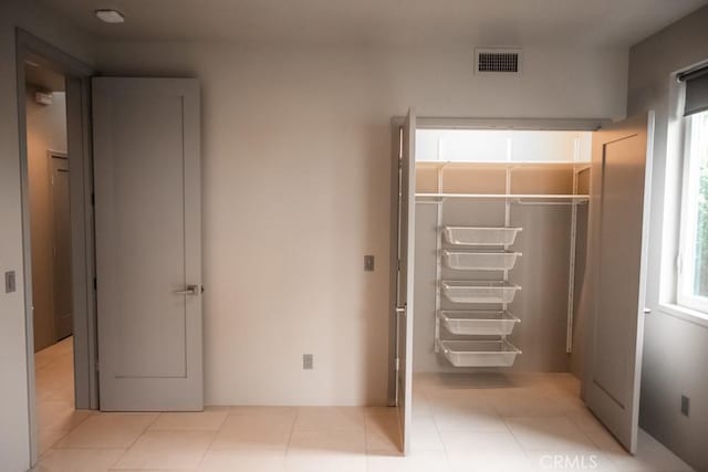 unfurnished bedroom featuring tile patterned flooring, visible vents, and a closet