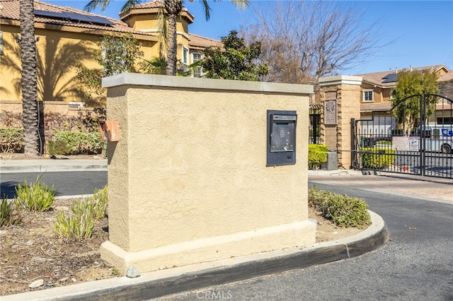 community / neighborhood sign featuring a gate and fence