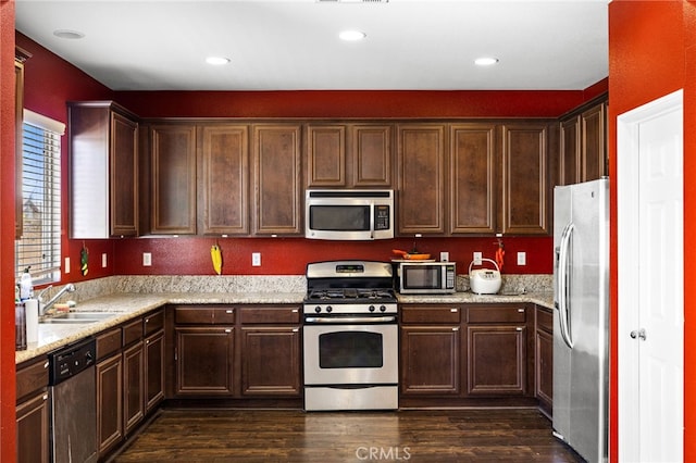 kitchen with stainless steel appliances, dark wood finished floors, a sink, and recessed lighting