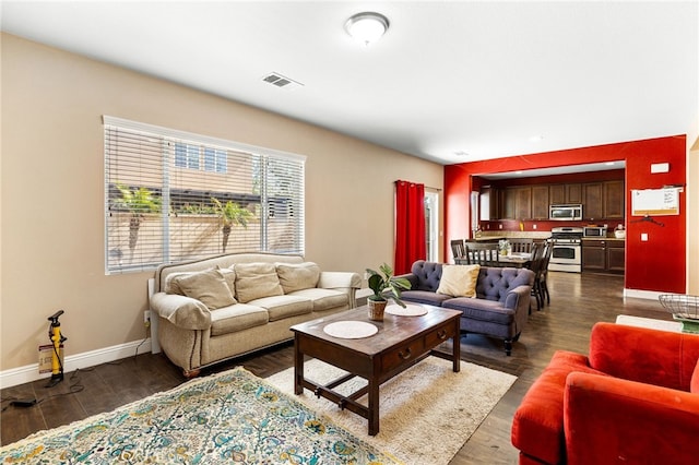 living area with baseboards, visible vents, and dark wood-style flooring