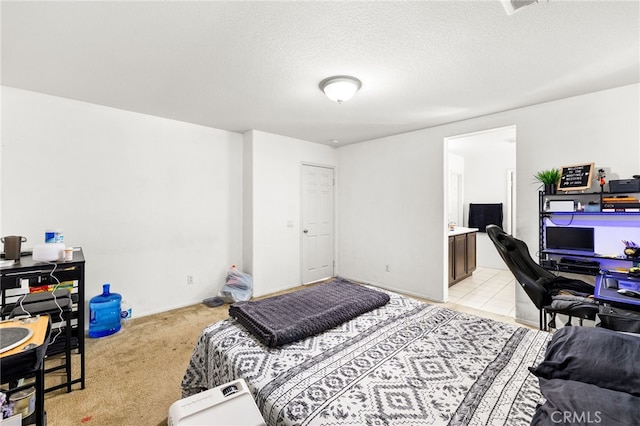 bedroom with light colored carpet, a textured ceiling, and ensuite bath