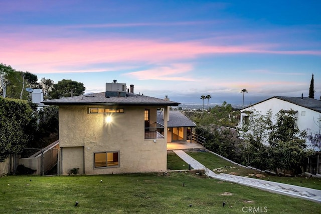 rear view of property featuring stucco siding, a yard, and fence