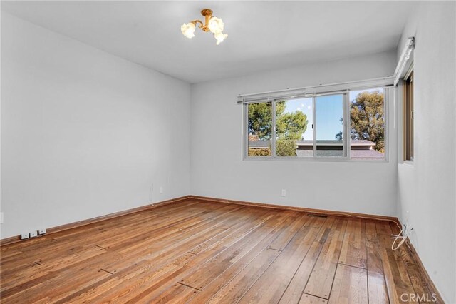 15470 Longbow, Sherman Oaks, CA 91403 - spare room with an inviting chandelier, baseboards, and hardwood / wood-style floors