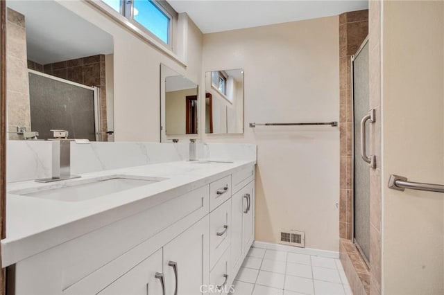 bathroom with double vanity, visible vents, a shower stall, and a sink