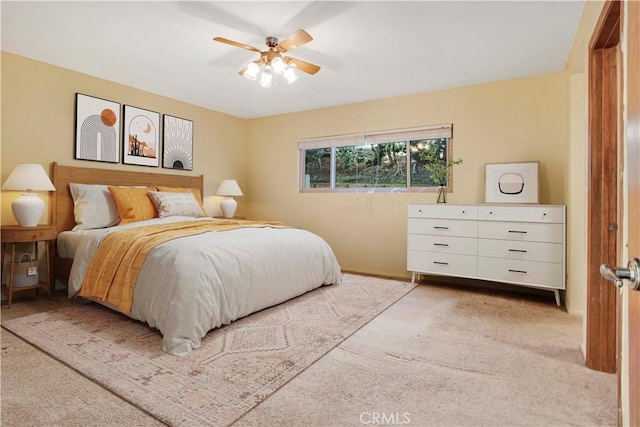 bedroom featuring light colored carpet, a ceiling fan, and baseboards