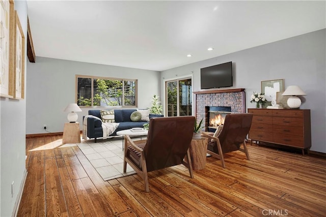 living room featuring baseboards, a brick fireplace, recessed lighting, and hardwood / wood-style floors