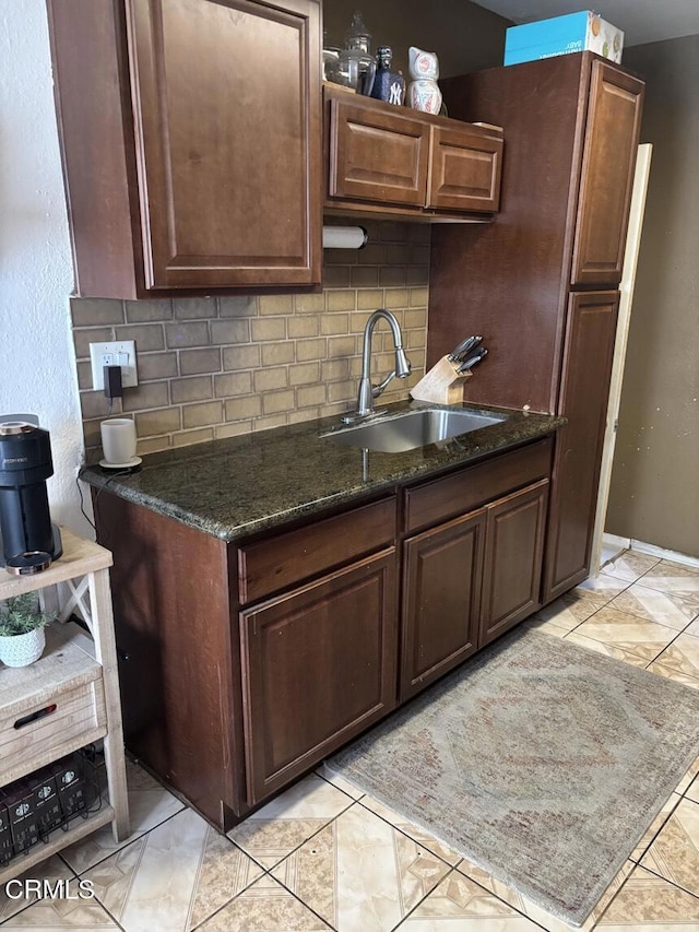 kitchen featuring dark stone counters, a sink, and backsplash