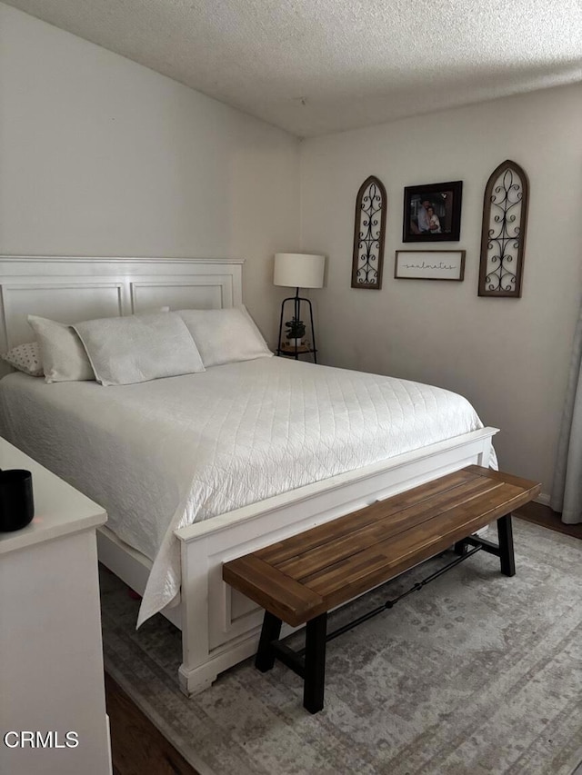 bedroom with a textured ceiling and wood finished floors