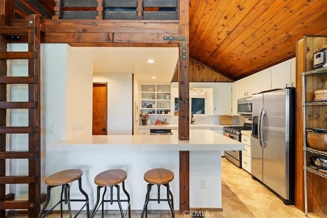 kitchen with wooden ceiling, appliances with stainless steel finishes, a peninsula, light countertops, and white cabinetry