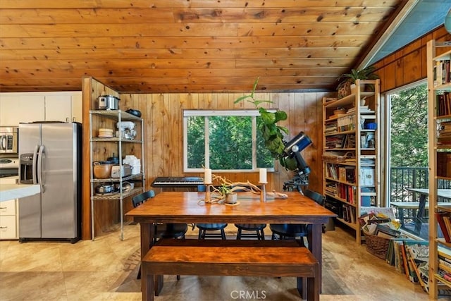 dining room featuring wood ceiling, wooden walls, and vaulted ceiling