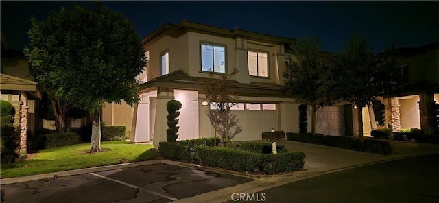 view of front of home with a yard, an attached garage, and stucco siding