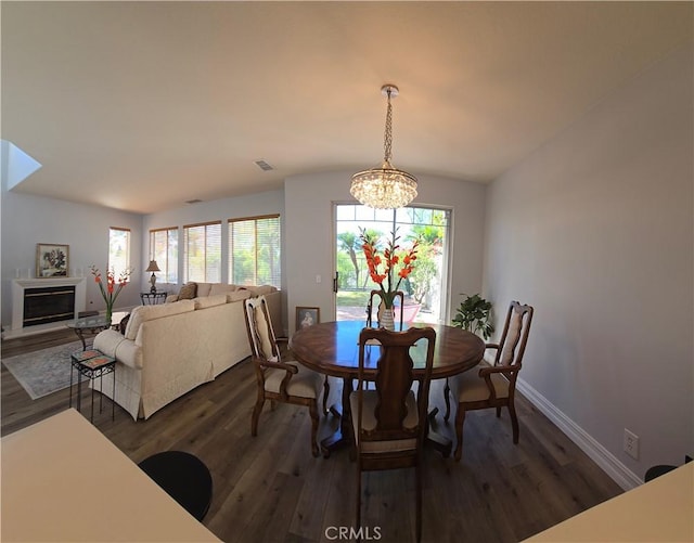 dining area featuring visible vents, dark wood-style flooring, a wealth of natural light, and a glass covered fireplace