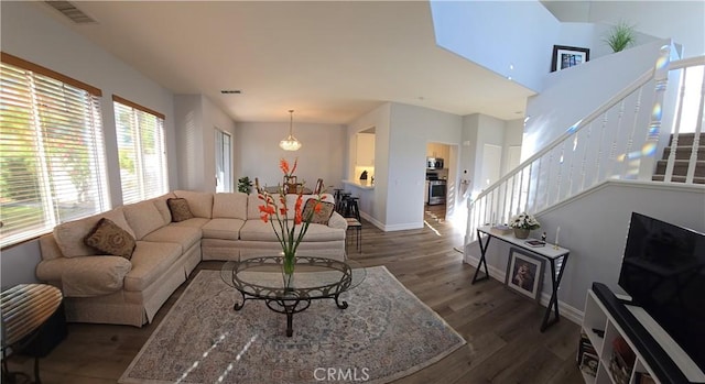 living area featuring visible vents, stairway, baseboards, and wood finished floors