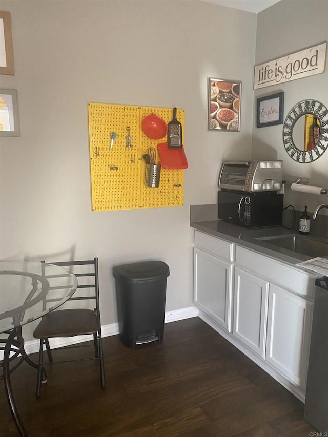 dining space featuring dark wood finished floors and baseboards