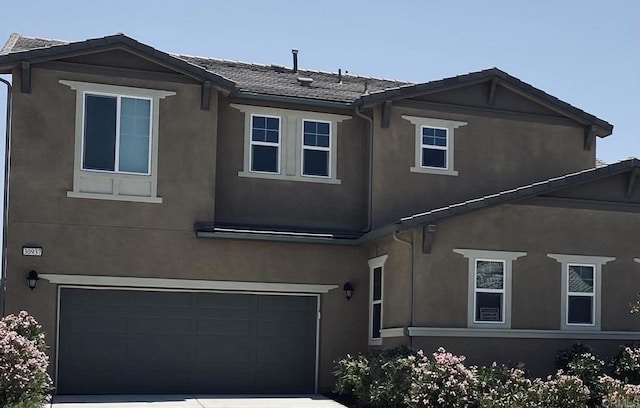 view of front facade with an attached garage, a tile roof, and stucco siding