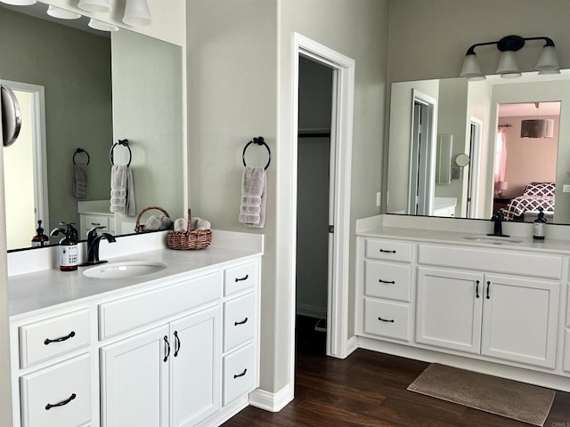 ensuite bathroom featuring two vanities, ensuite bathroom, a sink, and wood finished floors